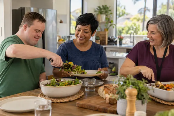 Housemates and a support worker sharing a meal in a bright shared kitchen
