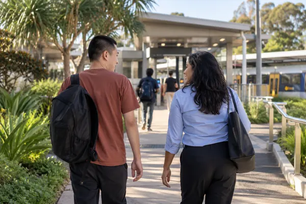 Support worker and participant walking towards a suburban train station