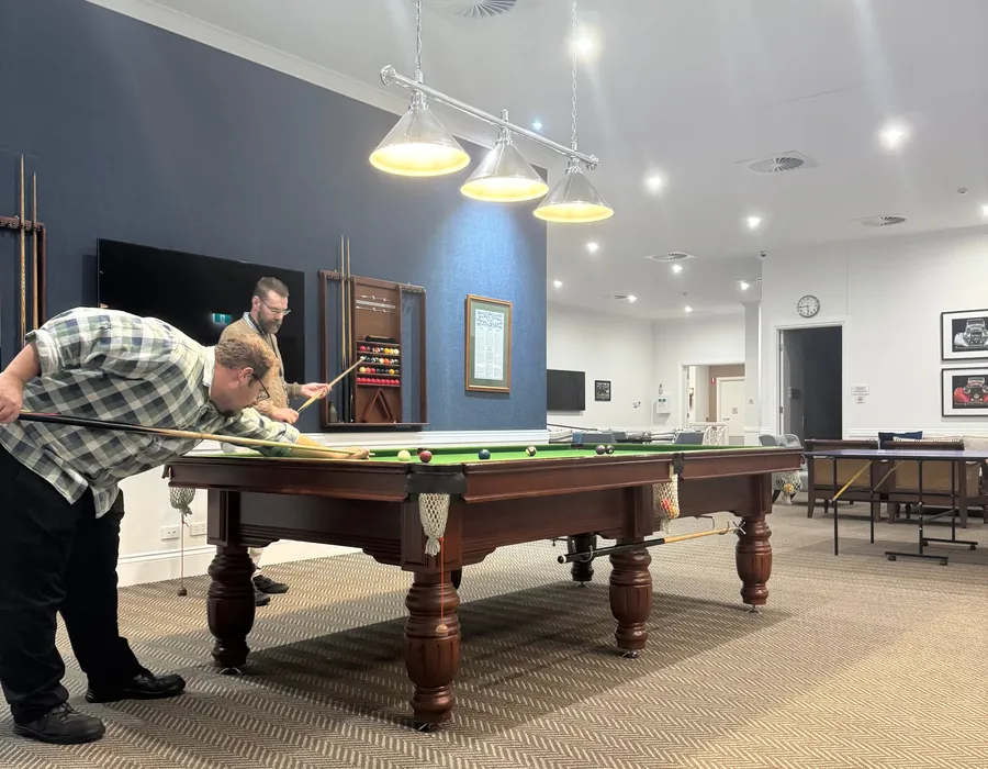 Participant lining up a shot at a pool table during a community outing